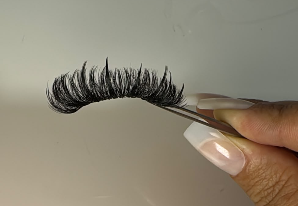 Tela artesanal de cílios segurada por uma pinça